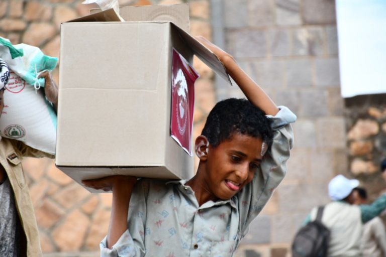 Yemeni boy happily carries his food parcel.