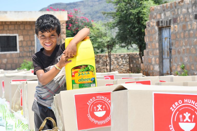 Yemeni boy stands next to a row of food parcels that will be handed out to the needy.