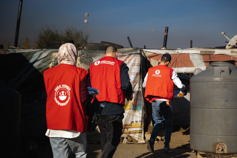 HCI workers walking in a refugee camp.